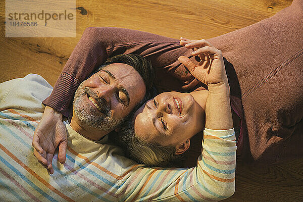 Lächelndes älteres Paar  das sich zu Hause auf dem Boden ausruht