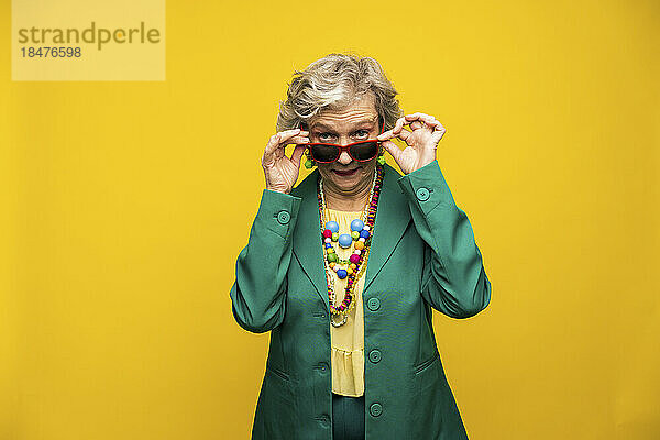 Ältere Frau mit Sonnenbrille vor gelbem Hintergrund