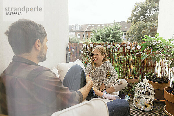 Vater und Tochter sitzen zusammen auf dem Balkon
