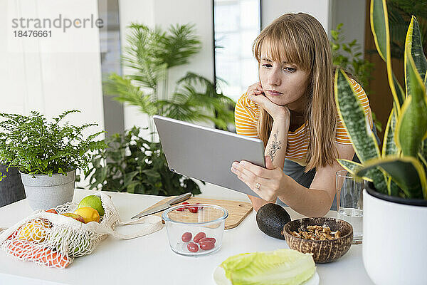 Frau schaut sich zu Hause Tutorial auf Tablet-PC an