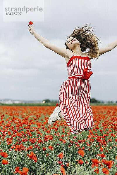 Cheerful young woman jumping at poppy field