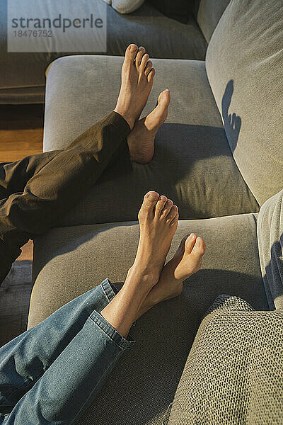 Die Beine eines Paares ruhen auf dem Sofa im heimischen Wohnzimmer