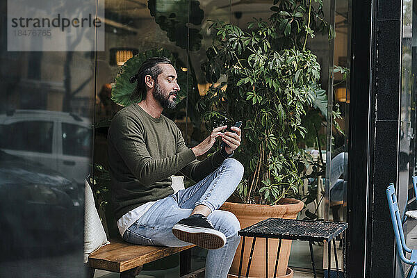 Reifer Mann benutzt Smartphone im Café