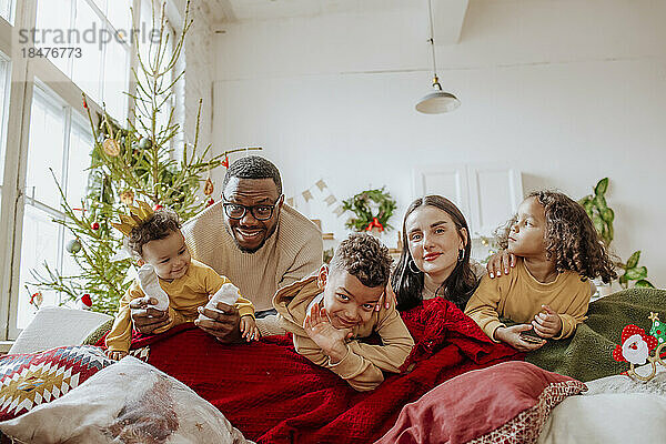 Glückliche Eltern mit Töchtern und Sohn  die Weihnachten im Wohnzimmer genießen