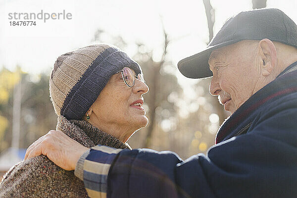 Älteres Paar trägt warme Kleidung und redet im Park miteinander