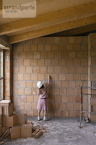 Girl with chalk drawing on brick wall at construction site