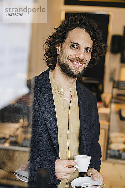 Lächelnder Geschäftsmann mit Kaffeetasse im Café