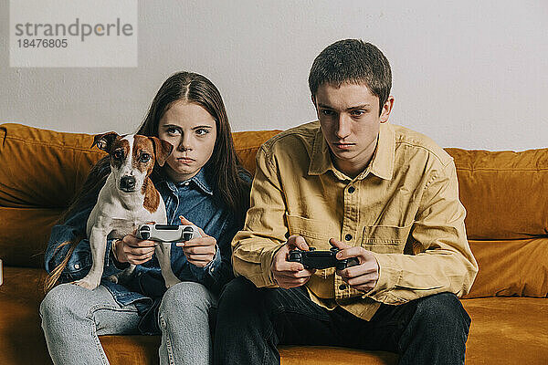 Paar mit Hund spielt Videospiel im Wohnzimmer