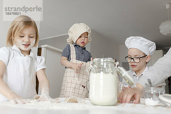Geschwister bereiten in der Küche Teig mit Mehl zu