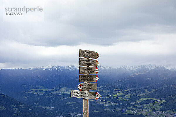 Wegweiser durch schneebedeckte Berge unter Wolken