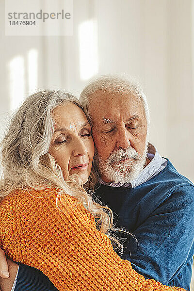 Liebevolles Seniorenpaar umarmt sich vor der Wand