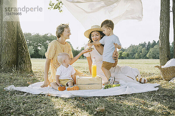 Glückliche Frauen genießen Picknick mit Söhnen im Park