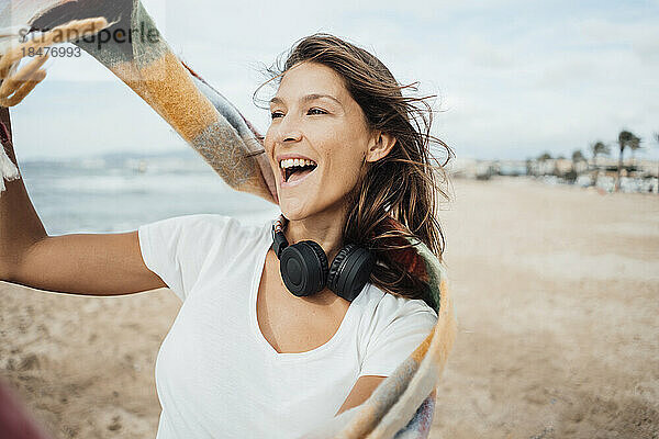 Fröhliche Frau mit Kopfhörern genießt den Strand