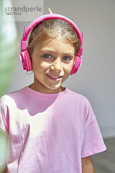 Lächelndes Mädchen mit rosa kabellosen Kopfhörern