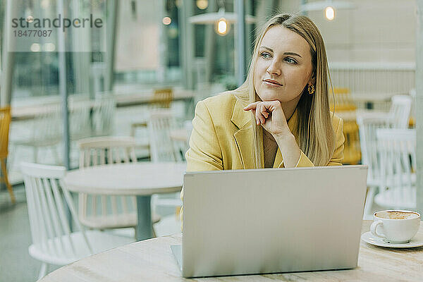 Nachdenkliche Geschäftsfrau mit Laptop am Tisch im Café