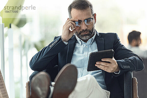 Geschäftsmann mit Brille und Tablet-PC am Arbeitsplatz