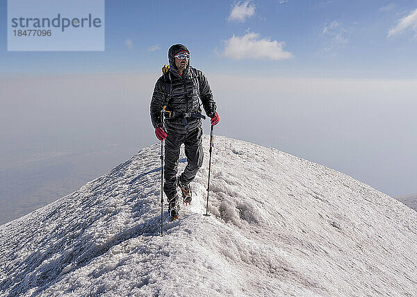 Mann wandert am Wochenende auf schneebedecktem Berg