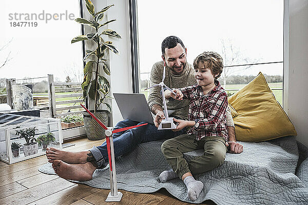 Vater und Sohn spielen zu Hause mit dem Modell einer Windkraftanlage