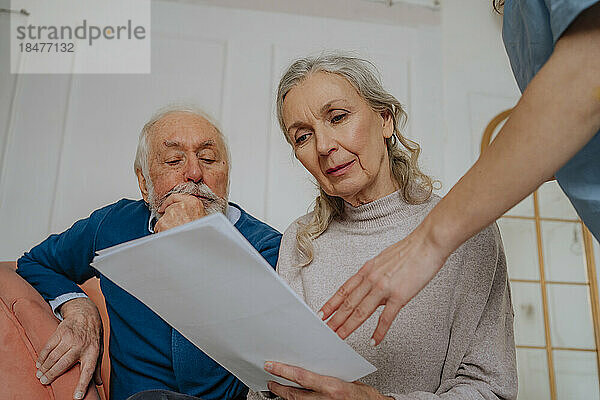 Ältere Frau liest medizinischen Bericht mit Mann zu Hause