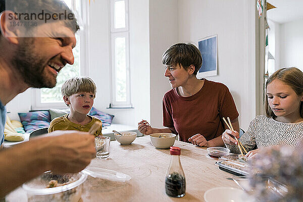 Eltern essen mit Kindern am Esstisch zu Hause