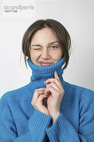 Playful young woman wearing turtleneck over white background