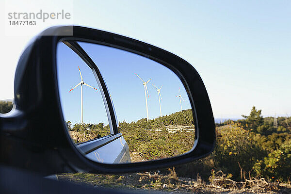 Windkraftanlagen spiegeln sich im Seitenspiegel des Autos
