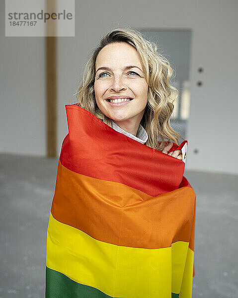 Glückliche Frau  gehüllt in mehrfarbige Flagge