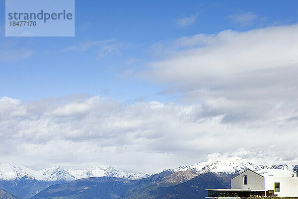 Kunstmuseum in der Nähe schneebedeckter Berge unter Wolken an einem sonnigen Tag