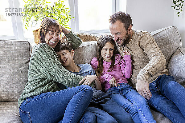 Happy man and woman spending time with children at home