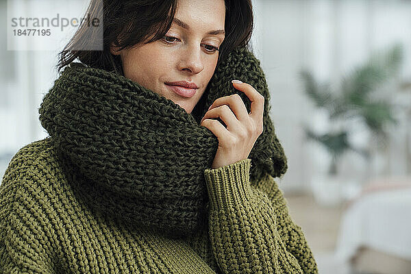 Smiling woman wearing green scarf at home