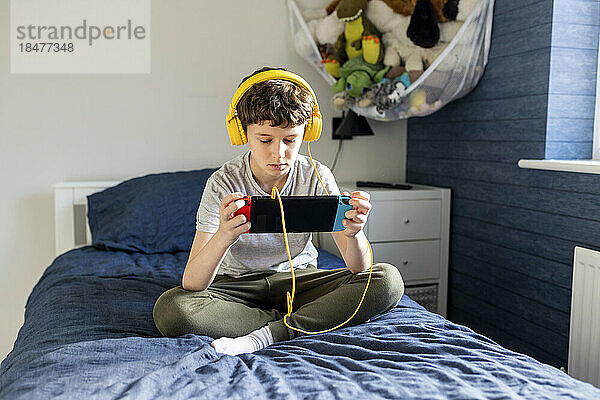 Junge mit Kopfhörern spielt Videospiel auf Tablet-PC