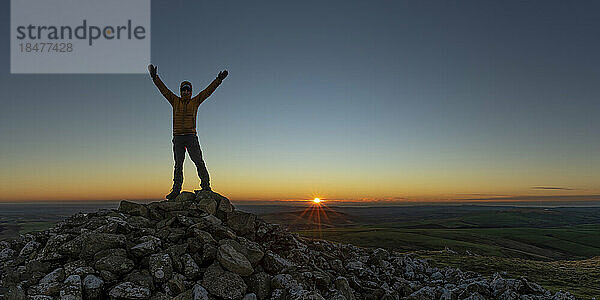 Mann mit erhobenen Armen steht auf dem Gipfel  Preseli Hills  Pembrokeshire  Wales
