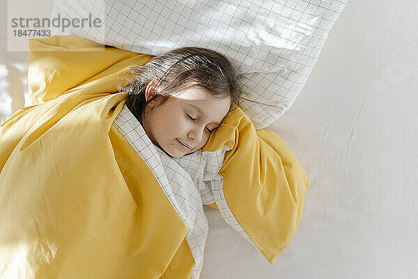 Mädchen schläft mit Decke auf dem Bett