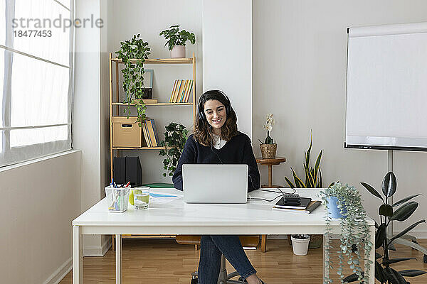 Lächelnde Geschäftsfrau mit Headset und Laptop im Büro
