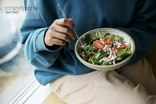 Woman holding bowl of fresh healthy salad