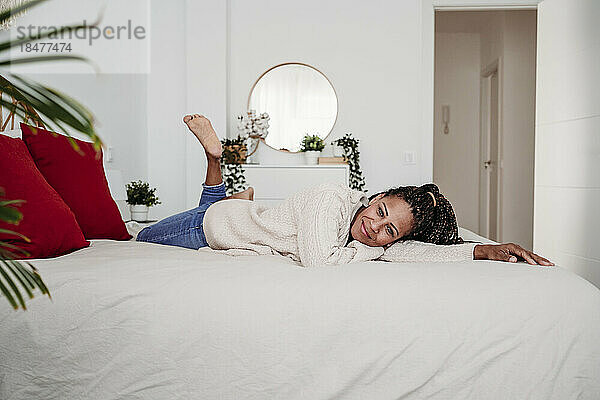 Lächelnde reife Frau entspannt sich zu Hause im Bett