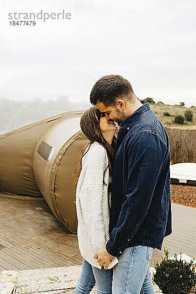 Glückliches junges Paar küsst sich im Kuppelzelt