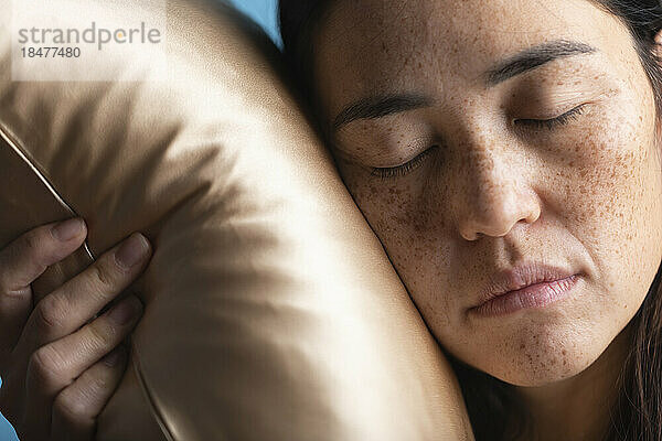 Woman with eyes closed sleeping on silk pillow