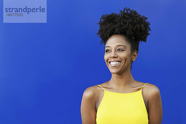 Thoughtful woman with Afro hairstyle against blue background