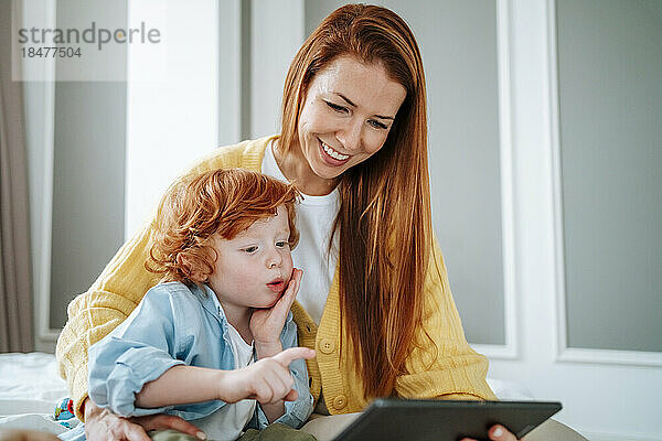 Lächelnde Mutter teilt Tablet-PC mit Sohn zu Hause