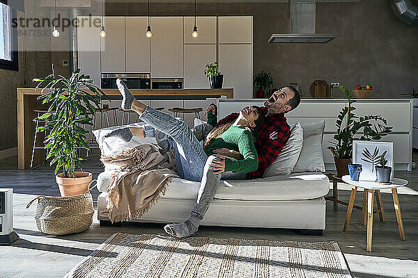 Verspieltes Paar genießt es zu Hause gemeinsam auf der Couch