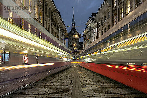 Switzerland  Bern Canton  Bern  Blurred motion of cable cars passing street at dusk