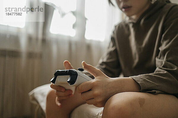Boy sitting on bed with controller at home