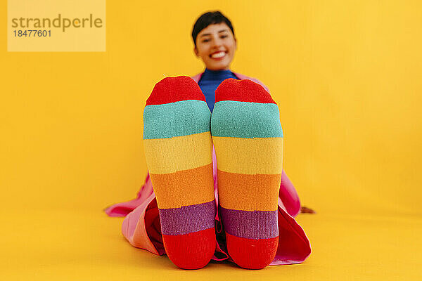 Woman wearing colorful socks over yellow background