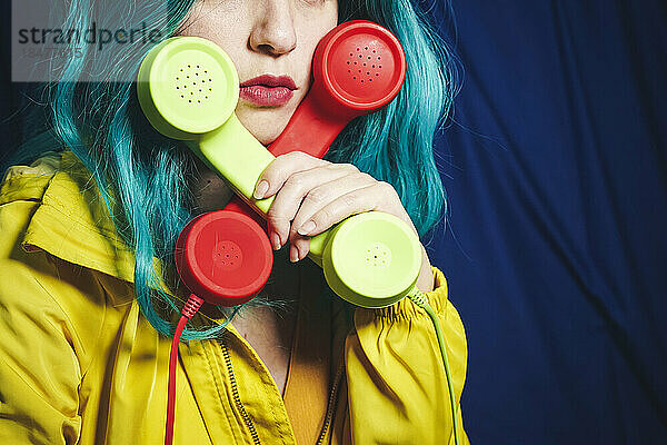 Frau hält grüne und rote Telefonhörer in Kreuzform