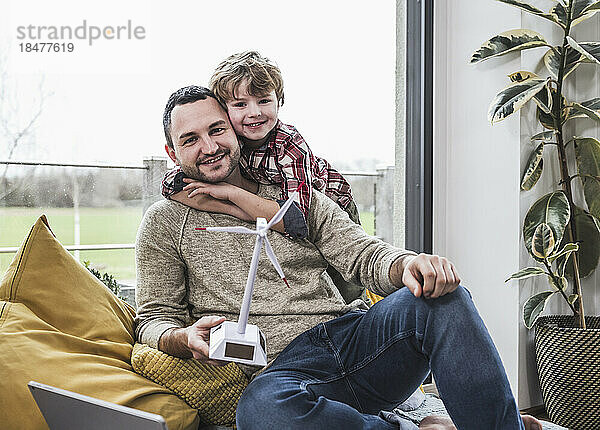 Lächelnder Vater und Sohn mit Windturbinenmodell zu Hause