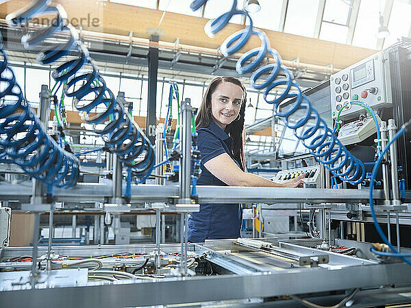 Lächelnder Ingenieur  der Maschinen in der Fabrik bedient