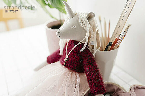 Unicorn toy with school supplies on table at home
