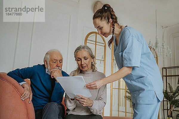 Ältere Patienten unterzeichnen Bericht durch lächelnde Pflegekraft zu Hause