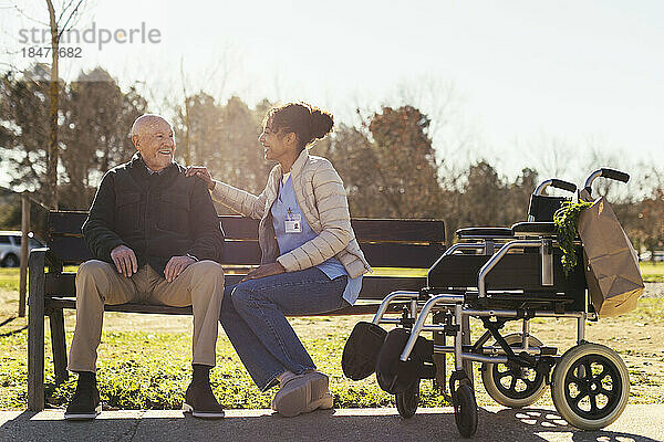 Lächelnder Hausmeister sitzt mit älterem Mann im Park